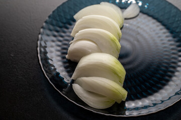 Thinly sliced ​​white onion on blue plate, onion sliced ​​for cooking.
Vegetarianism. Home...
