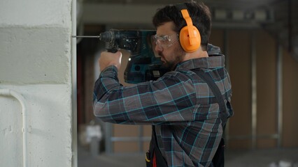 Repairman builder man Caucasian guy drilling wall with hammer drill repair renovation building...