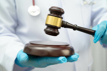 Asian doctor holding court hammer for and crime law justice, forensic medicine.