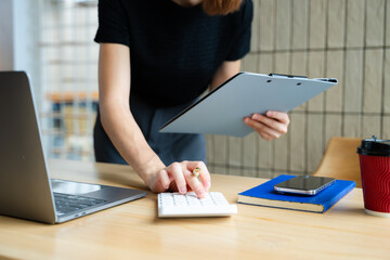 Close up of businesswoman or accountant hand typing laptop working to calculate on desk about cost