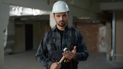 Portrait man builder repairman engineer angry guy hitting hammer on construction site building...