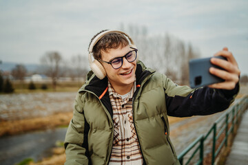 Young adult caucasian student smile and using smart phone to talk or take self portrait