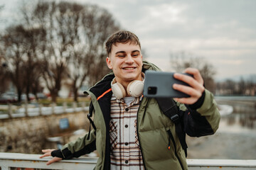 Young adult caucasian student smile and using smart phone to talk or take self portrait
