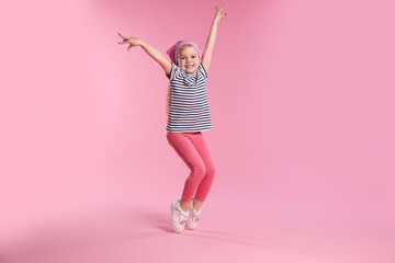 Cute little girl dancing on pink background