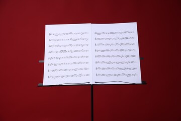 Note stand with music sheets on red background