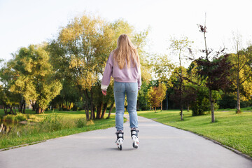 Young woman roller skating in park, back view