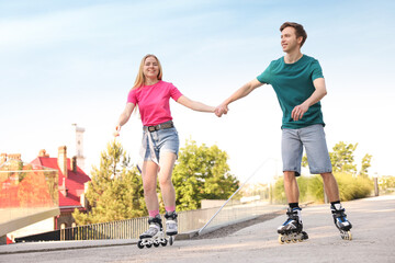 Happy couple roller skating together on street