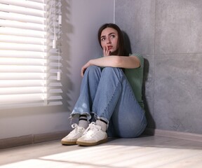 Woman suffering from paranoia near window at home