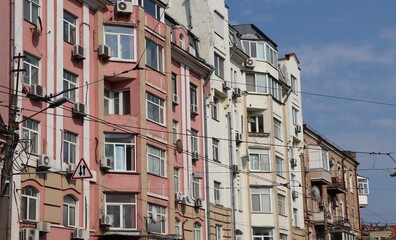 Street View of Residential Buildings in Urban Area with Parked Cars, Traffic Signs, and Varied Architectural Facades
