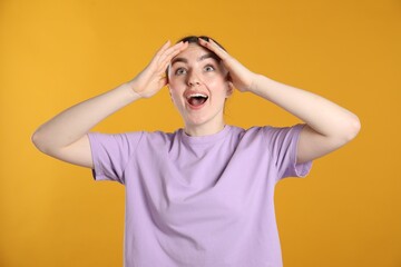 Portrait of surprised woman on orange background