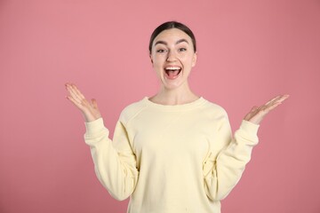 Portrait of surprised woman on pink background