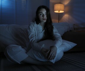 Frustrated woman with pillow suffering from insomnia on floor at home