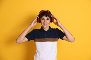 Teenage boy in headphones on orange background
