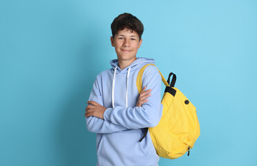 Teenage boy with backpack on light blue background