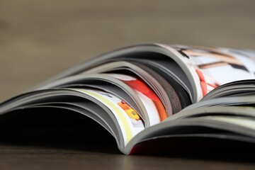 Different open magazines on wooden table, closeup
