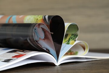 One open magazine on wooden table, closeup