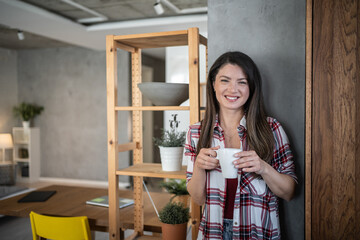 Smiling woman enjoying morning coffee in modern apartment