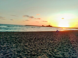 sunset on the sea in Bosa marina in the summer with a couple staring at the horizon