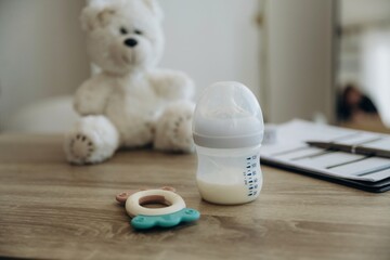 Baby bottle and teddy bear toy on the wooden table