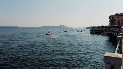 Sailboats drifting across Lake Maggiore in Belgirate, highlighting picturesque Italian landscape...