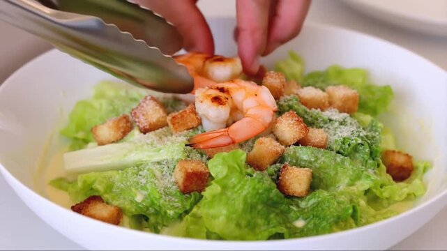 A fresh Caesar salad topped with grilled shrimp, crispy romaine lettuce, parmesan cheese, crunchy croutons, and creamy Caesar dressing, served on a white plate, restaurant-style presentation