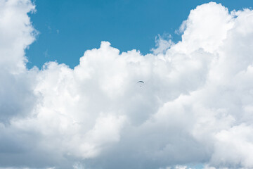 Paraglieder flies in the sky on a sunny day, clouds in the background, Switzerland, Swiss Alps. Extreme sport, leisure activities, sunny day, outdoors, landscape.