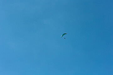 Paraglieder flies in the blue sky on a sunny day, Switzerland, Swiss Alps. Extreme sport, leisure...