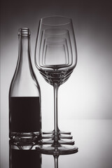 Empty wine glasses in a row and bottle on a reflective background.Shallow depth of  field.