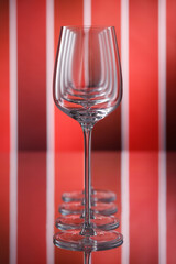 Row of empty wine glasses on a red reflective background. Shallow depth of  field. The idea, the concept of different varieties and shades of red wine. NO AI