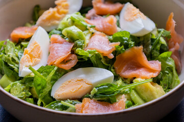 delicious and healthy salad with smoked salmon, boiled egg, greens, and fresh vegetables