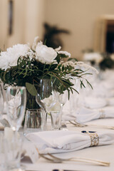 Elegant wedding banquet table decorated with white florals, glassware, and folded napkins for a...