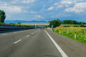 driving on the autostrada a21 toward brescia in northern italy during a sunny day with blue skies and clouds