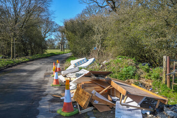 Shenley, UK. 8th April 2010. The illegal practice of fly-tipping down a country lane near farmland in Hertfordshire. Mattresses and broken household furniture have been dumped by the roadside.