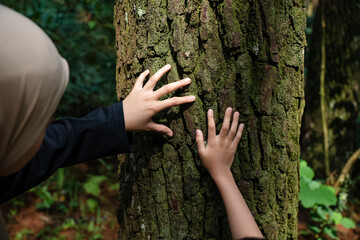 mother and her child looking at and touching a tree, nature education for children concept