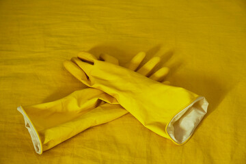 Bright yellow rubber gloves placed neatly on a vibrant yellow surface, highlighting cleaning tools...