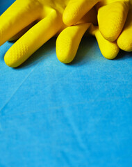 Bright yellow cleaning gloves resting on a blue surface in a household setting during daylight hours