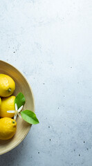 Wooden bowl with organic fresh lemons and lemon flower on gray concrete background, healthy food,...