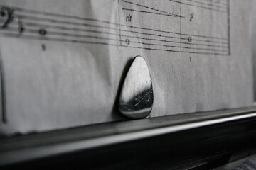guitar pick in front of a sheet music