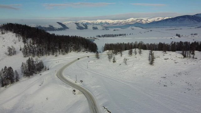 Drone footage of snowy mountains, valleys, and forests in Ust-Koksa, Altai Republic, Russia, under clear skies, showing the remote region&rsquo;s beauty during winter.