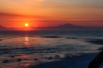 Obraz premium Vibrant Sunrise Over a Snowy Winter Seascape