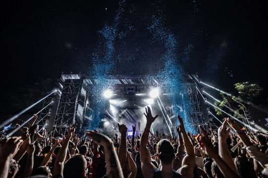 Crowd raising hands at music festival with falling blue confetti - Powered by Adobe