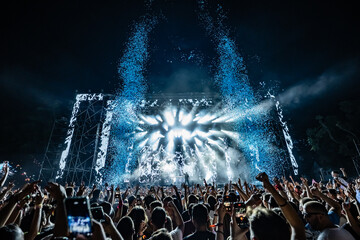 Crowd enjoying an outdoor music festival with water jets and confetti