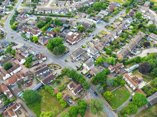 Drone high level view of a typical British village. The centre of the image shows pubs, convince store and coffee shops near the large clump of trees.