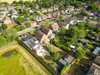 Drone view of extended detached houses seen in rural England. To the left is a field which is currently being planned as a forthcoming housing development.