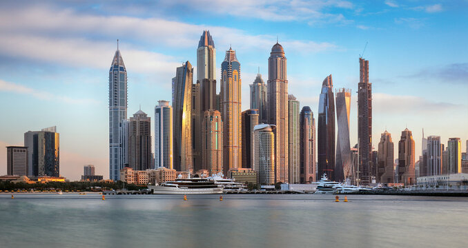 Modern buildings with gold reflection of sunset on Dubai Marina bay view from Palm Jumeirah, UAE.