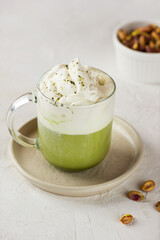 Matcha latte, green tea latte is a drink made from matcha powder mixed with milk, cream and pistachio syrup. Trendy drink. Vertical orientation.