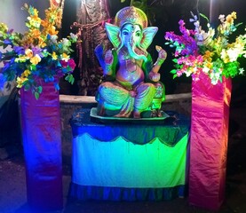 Lord Ganesha Idol with Colorful Flowers and Lights – Hindu God Ganpati Decorated for Festival or Puja Celebration