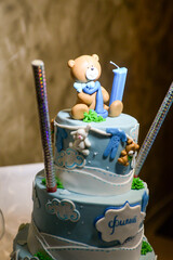 A three-tier blue and white birthday cake decorated with fondant, figurines in the shape of bears and a bunny with the male name Philip written in Cyrillic.