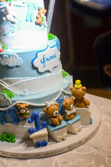 A three-tier blue and white birthday cake decorated with fondant, figurines in the shape of bears and a bunny with the male name Philip written in Cyrillic.