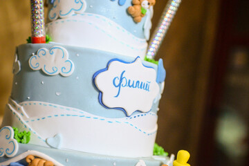 A three-tier blue and white birthday cake decorated with fondant, figurines in the shape of bears and a bunny with the male name Philip written in Cyrillic.